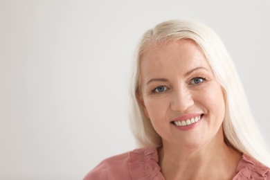 Portrait of beautiful older woman against light background with space for text