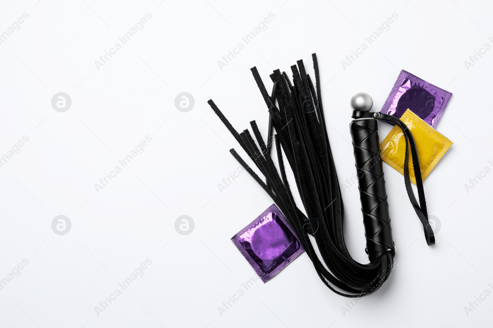 Photo of Whip and condoms on white background, top view. Sex game