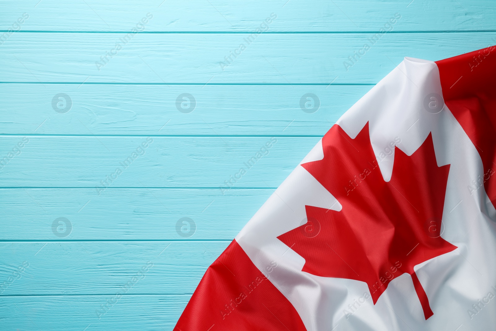 Photo of Flag of Canada on turquoise wooden table, top view. Space for text