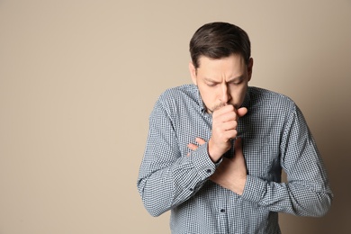 Photo of Man suffering from cough on color background. Space for text