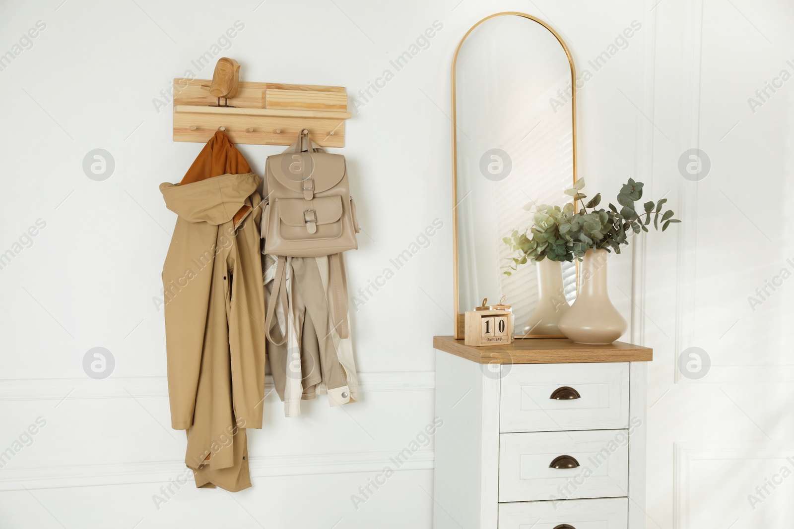 Photo of Stylish hallway interior with coat rack, eucalyptus branches and mirror