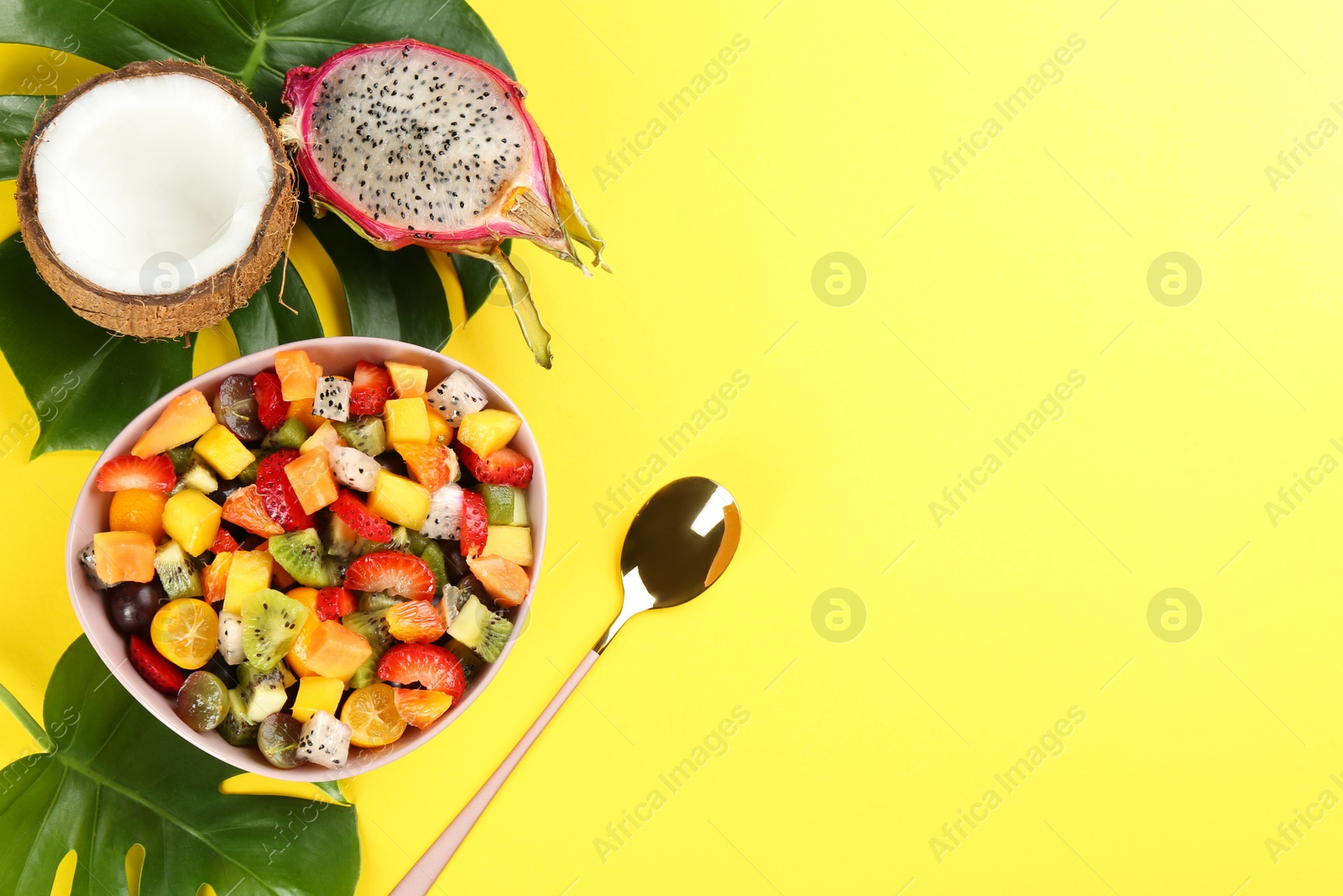 Photo of Flat lay composition with delicious exotic fruit salad on yellow background. Space for text