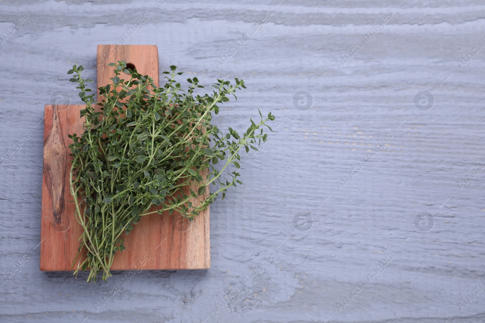 Photo of Bunch of aromatic thyme on light grey wooden table, top view. Space for text