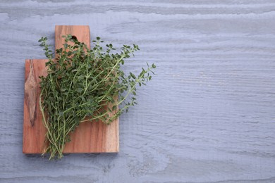 Photo of Bunch of aromatic thyme on light grey wooden table, top view. Space for text