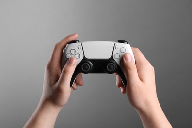 Photo of Woman using wireless game controller on grey background, closeup
