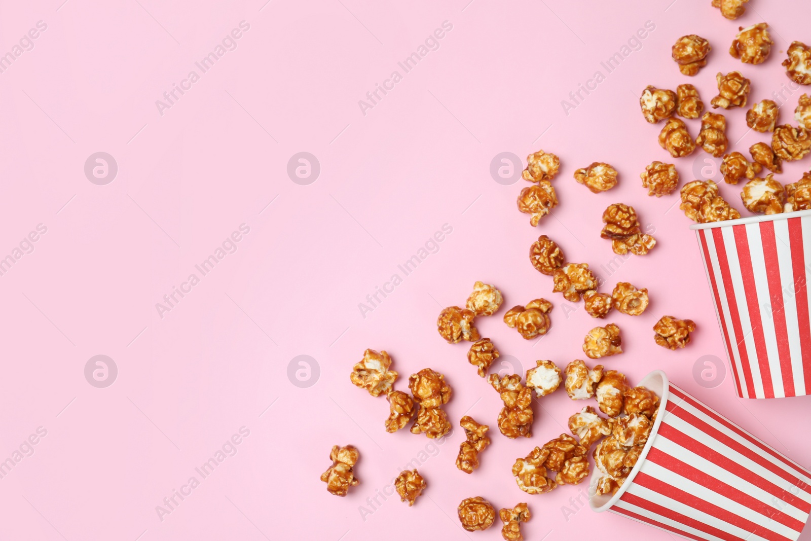 Photo of Overturned paper cups with caramel popcorn on color background, top view. Space for text