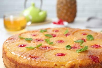 Photo of Tasty pineapple cake with cherries and mint on table, closeup