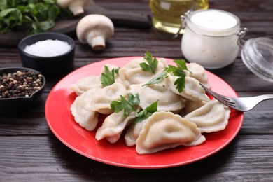 Photo of Delicious dumplings (varenyky) with potatoes and parsley served on brown wooden table
