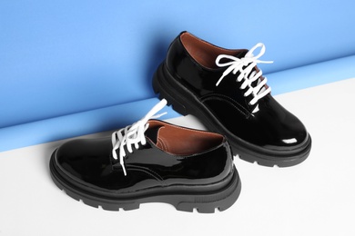 Stylish leather shoes with white laces on color background