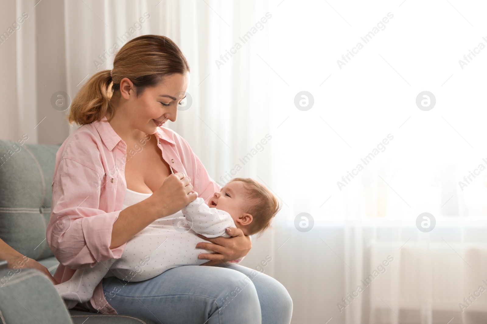 Photo of Young woman with her cute baby at home. Space for text