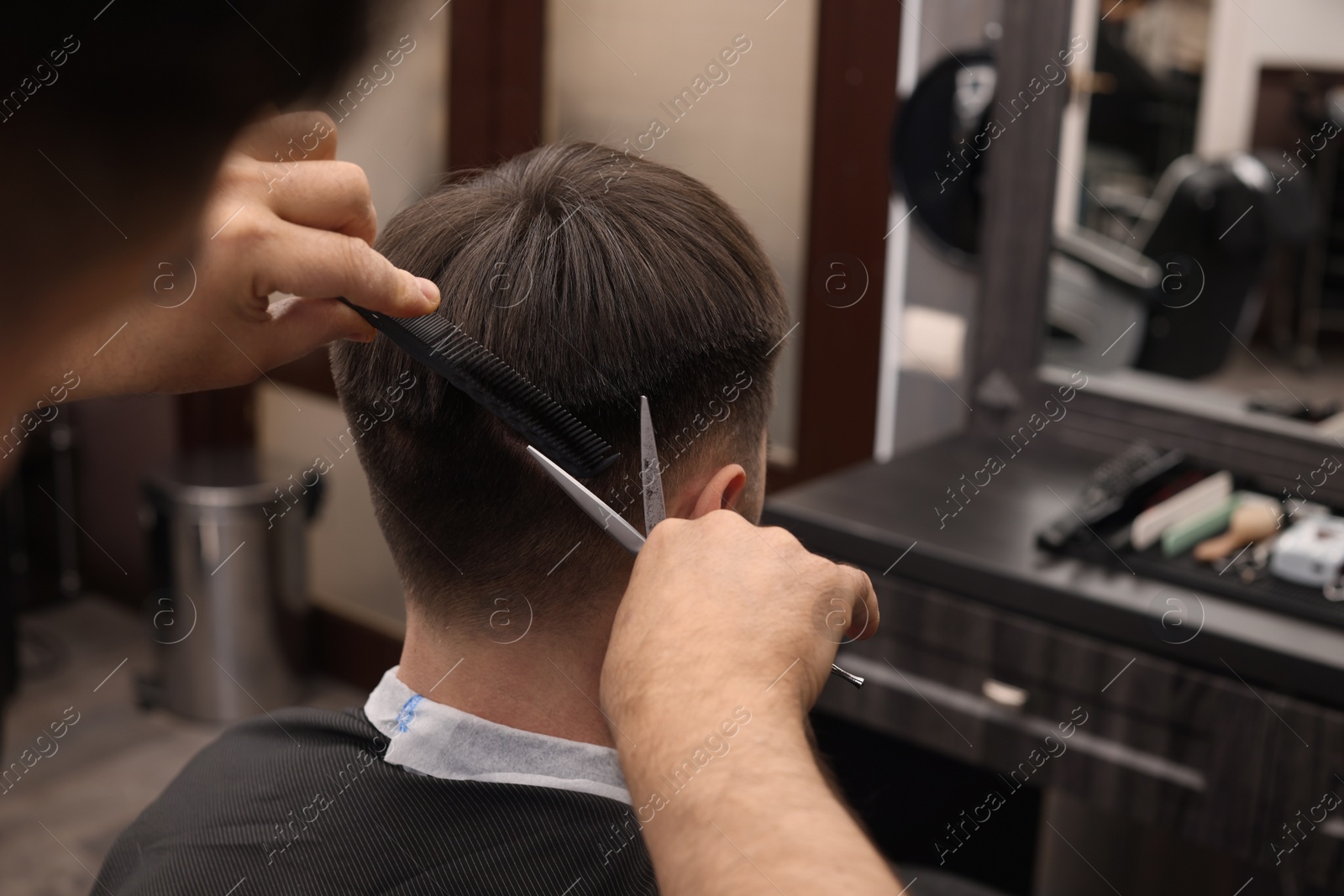 Photo of Professional hairdresser cutting man's hair in barbershop