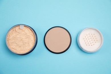 Photo of Three different face powders on light blue background, flat lay