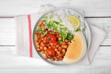 Delicious chickpea curry, rice and flatbread on white wooden table, top view
