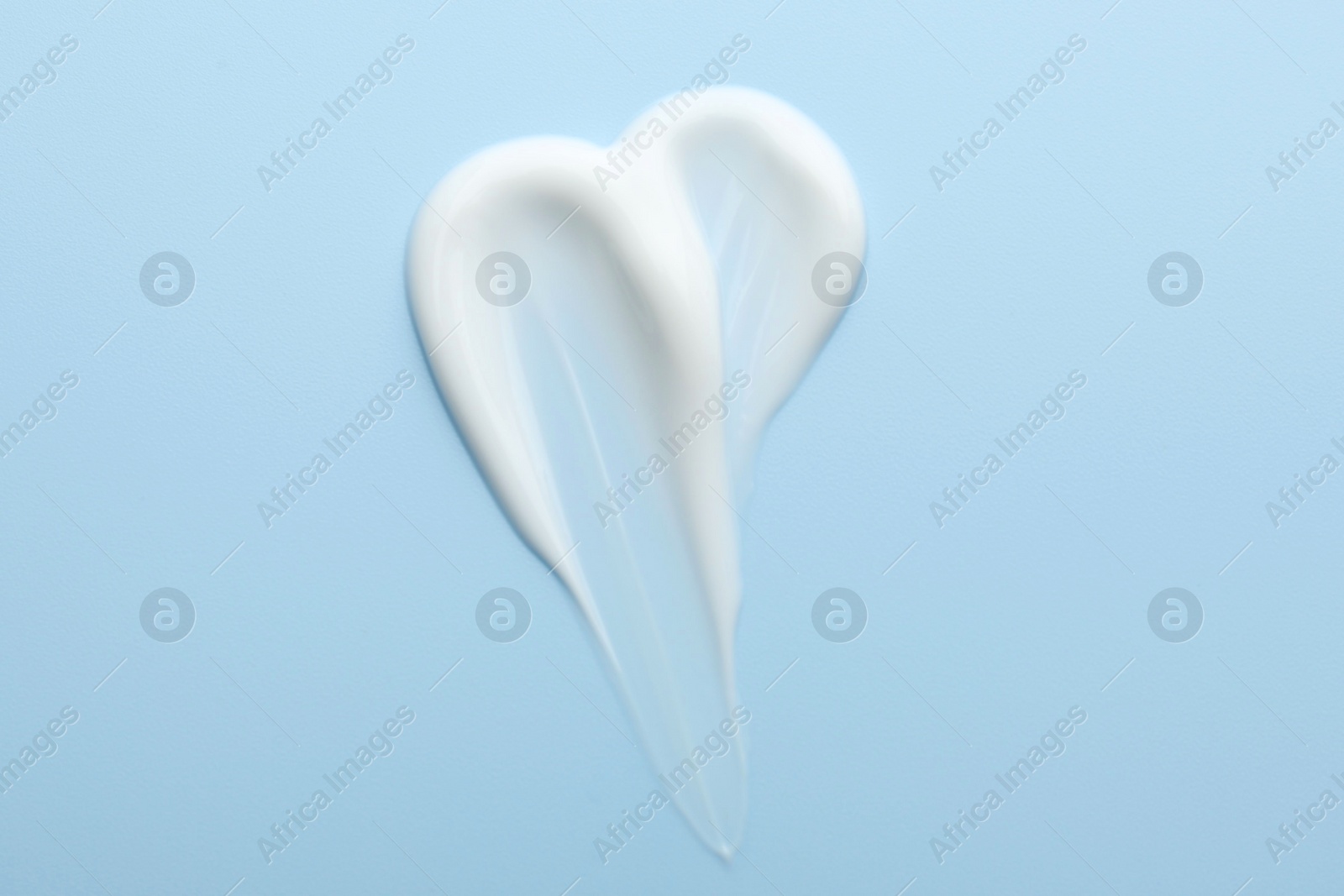 Photo of Sample of face cream on light blue background, top view