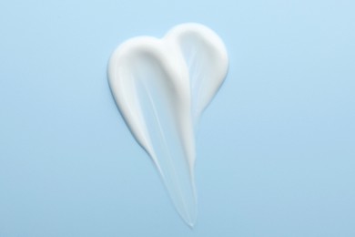 Photo of Sample of face cream on light blue background, top view