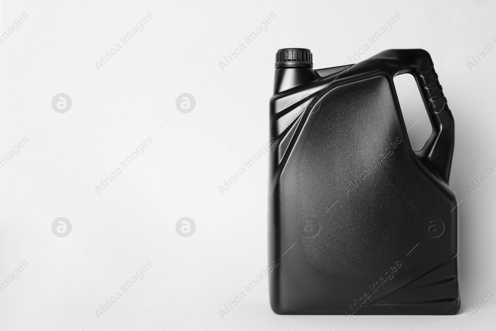 Photo of Motor oil in black canister on light background, space for text