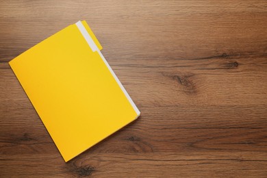 Yellow file with documents on wooden table, top view. Space for text