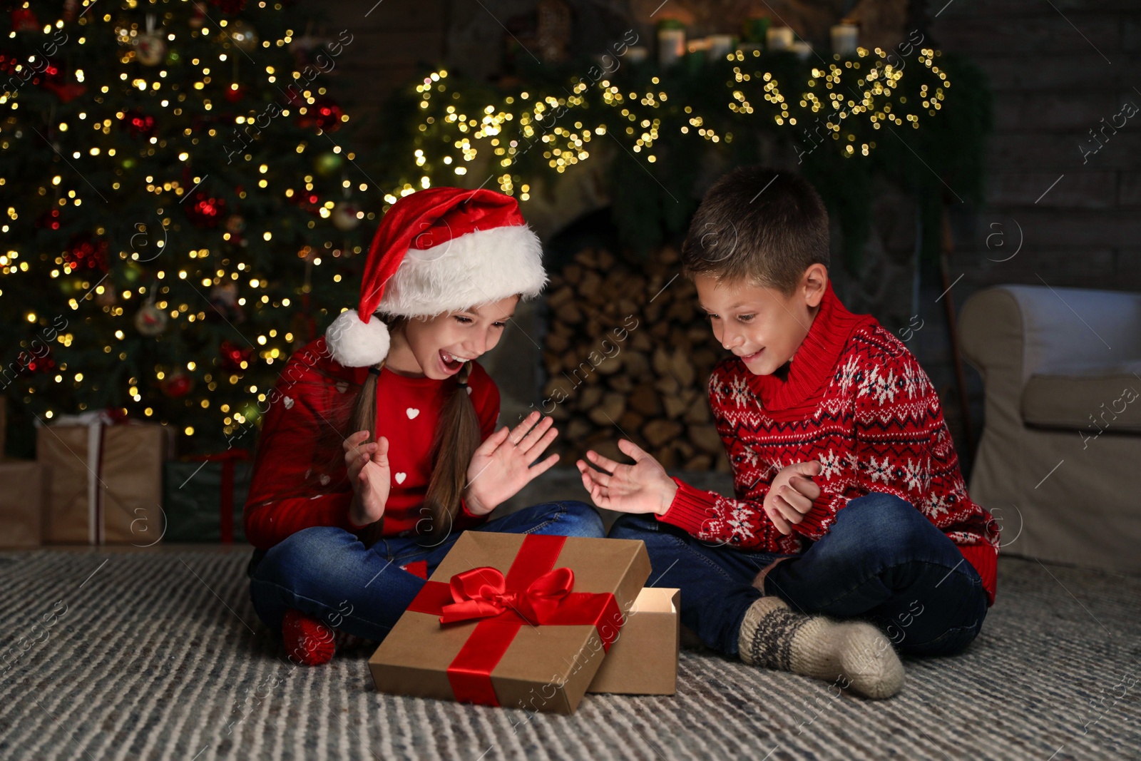 Photo of Happy children with magic Christmas gift on floor at home