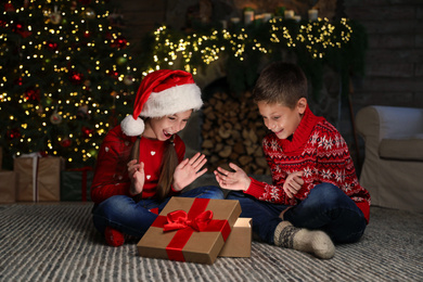 Photo of Happy children with magic Christmas gift on floor at home