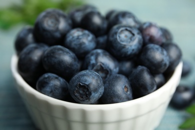 Photo of Bowl full of tasty ripe blueberries on table, closeup