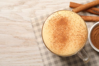 Photo of Delicious eggnog with cinnamon on wooden table, top view. Space for text