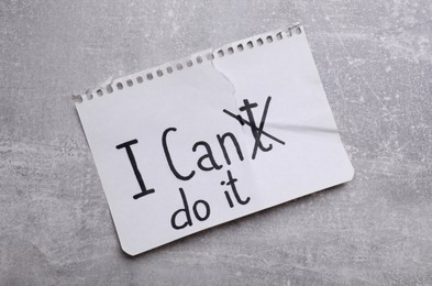 Photo of Motivation concept. Changing phrase from I Can't Do It into I Can Do It by crossing out letter T on light grey table, top view