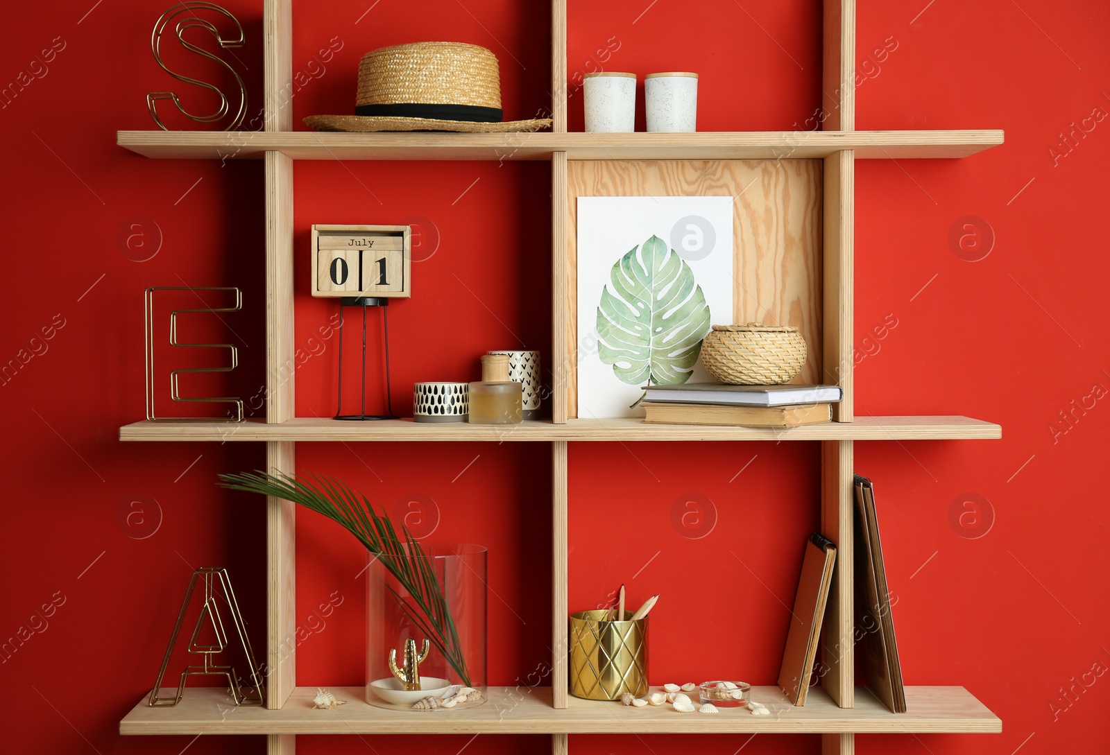 Photo of Stylish wooden shelves with decorative elements on red wall