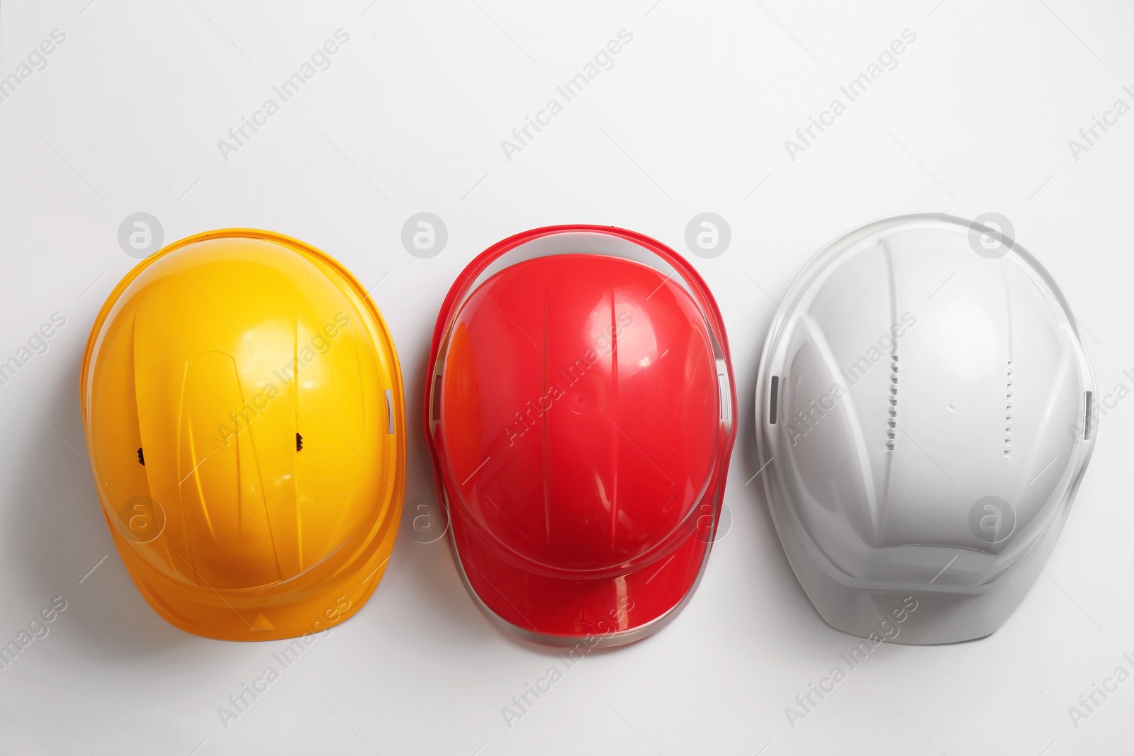 Photo of Flat lay composition with hard hats on white background. Safety equipment