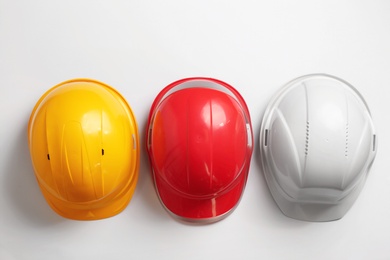 Flat lay composition with hard hats on white background. Safety equipment