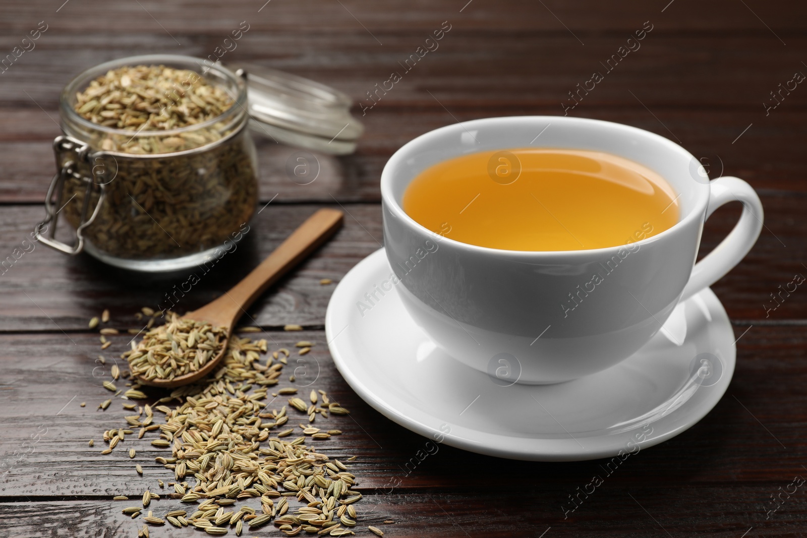 Photo of Fennel tea in cup and seeds on wooden table, closeup