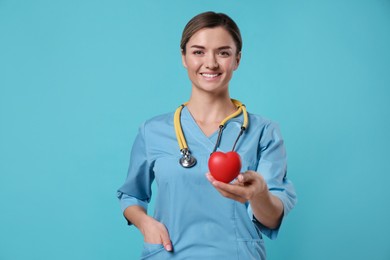 Photo of Doctor with stethoscope and red heart on light blue background. Cardiology concept