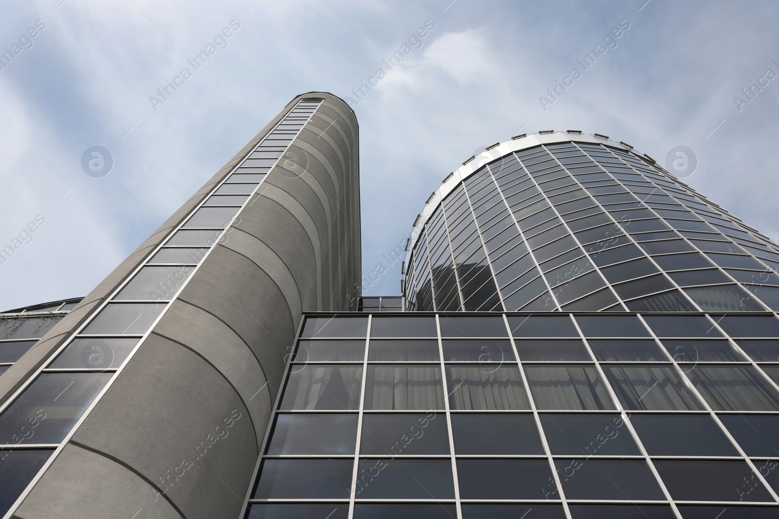 Photo of Modern building with tinted windows against sky, low angle view. Urban architecture