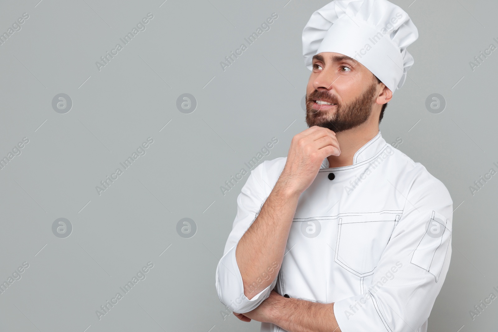 Photo of Smiling mature chef on grey background, space for text