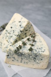 Photo of Tasty blue cheese with thyme on grey table