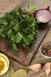 Board with fresh parsley, peppercorns and other products on wooden table, closeup
