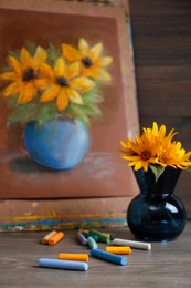 Photo of Yellow flowers, beautiful drawing and set of colorful pastels on wooden table