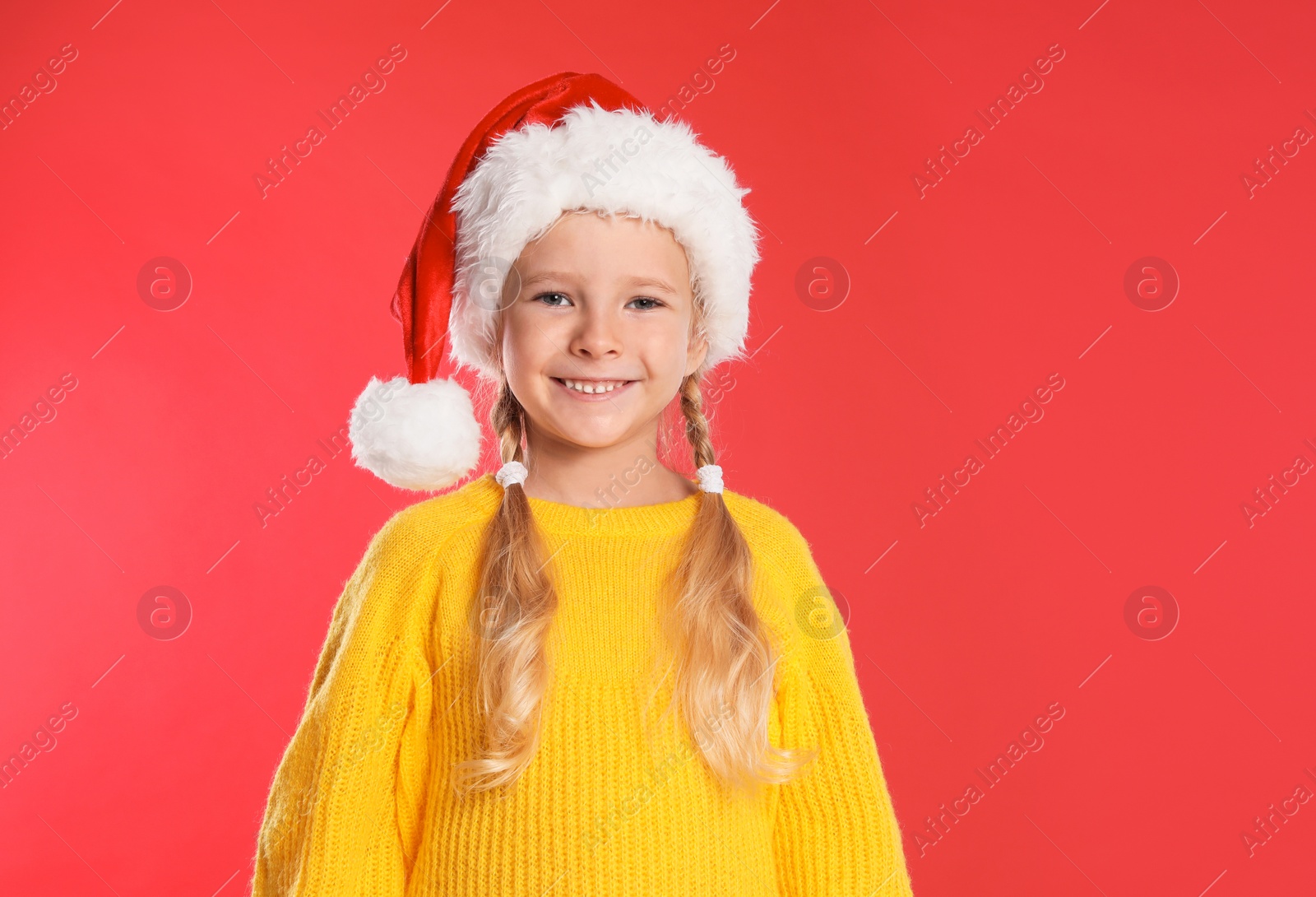 Photo of Happy little child in Santa hat on red background. Christmas celebration