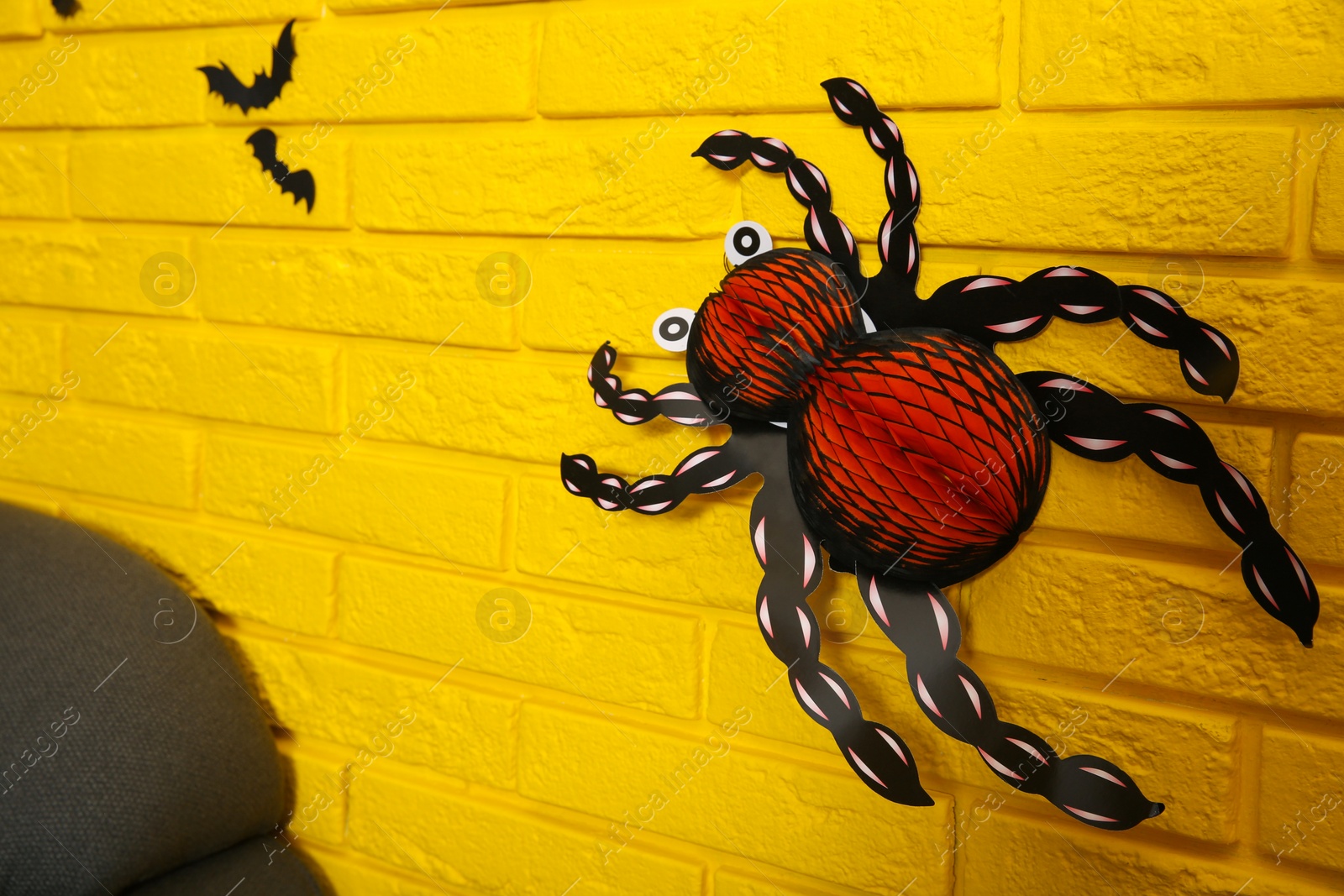 Photo of Yellow brick wall decorated for Halloween in room, focus on spider