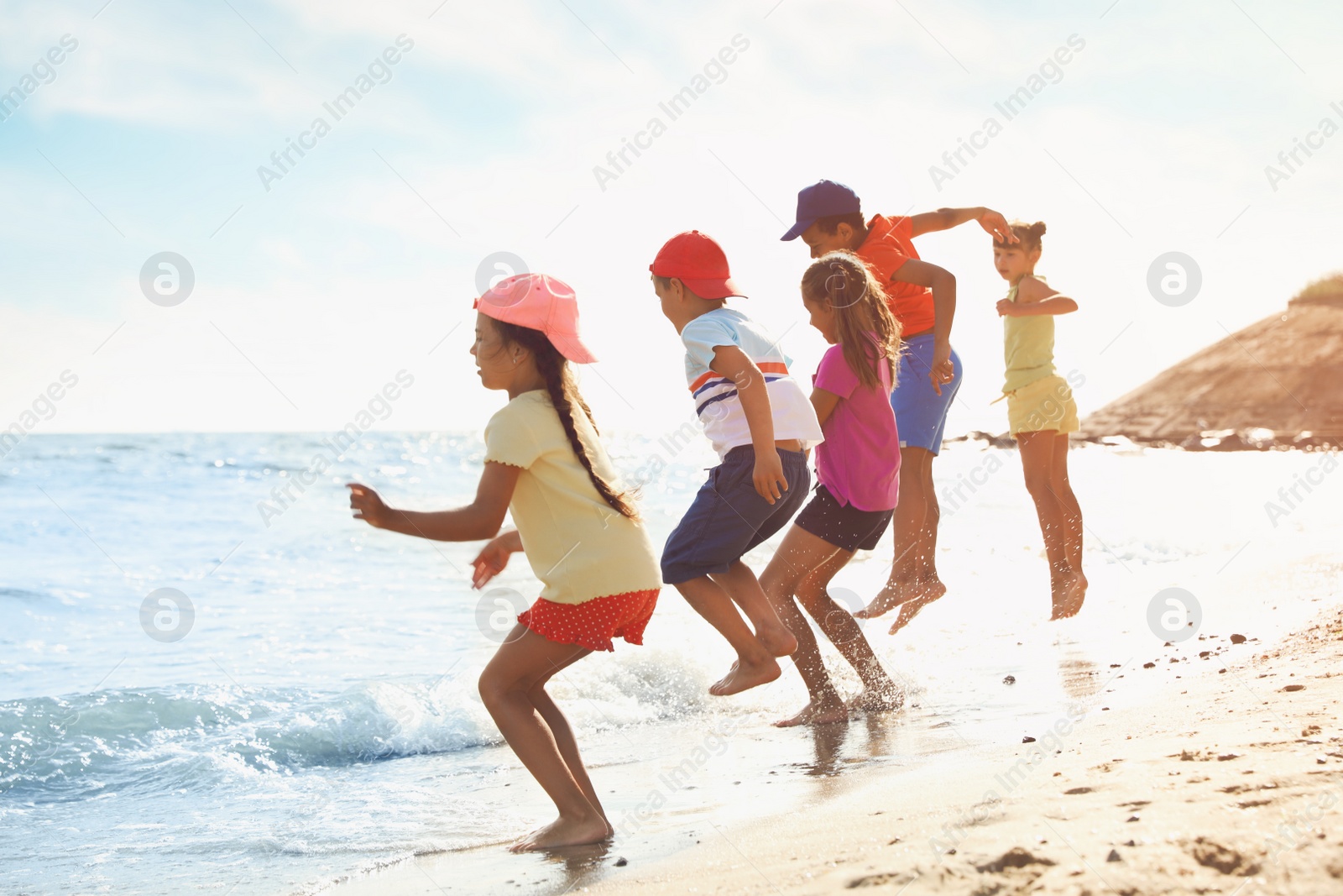 Photo of Cute children enjoying sunny day at beach. Summer camp