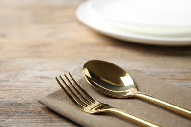 Cutlery set and dishware on wooden table, closeup