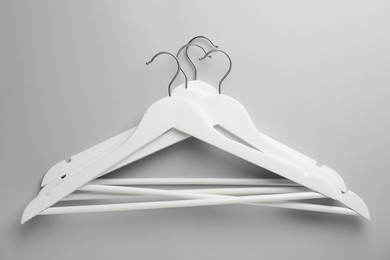 Photo of White hangers on light gray background, top view