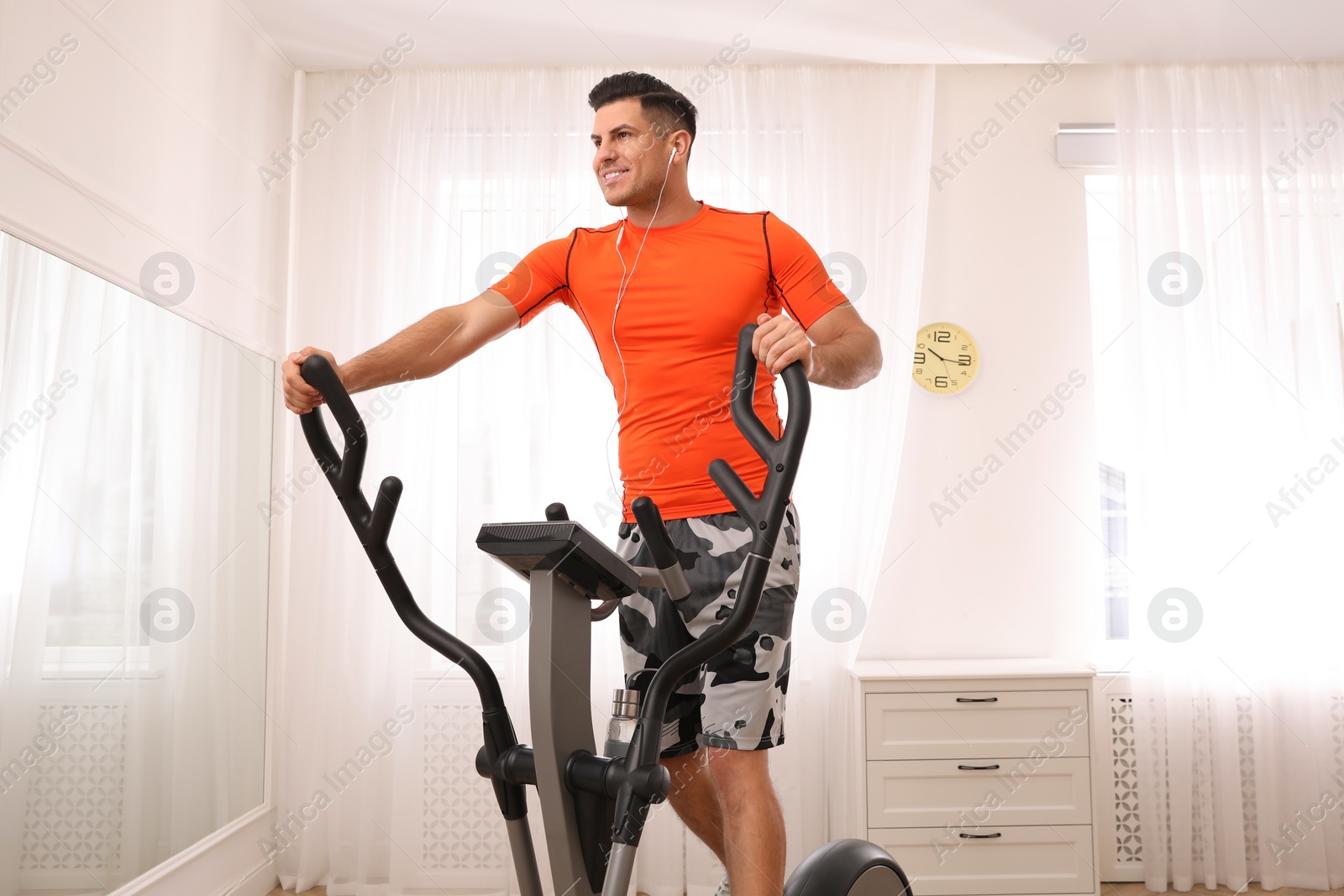 Photo of Man using modern elliptical machine at home