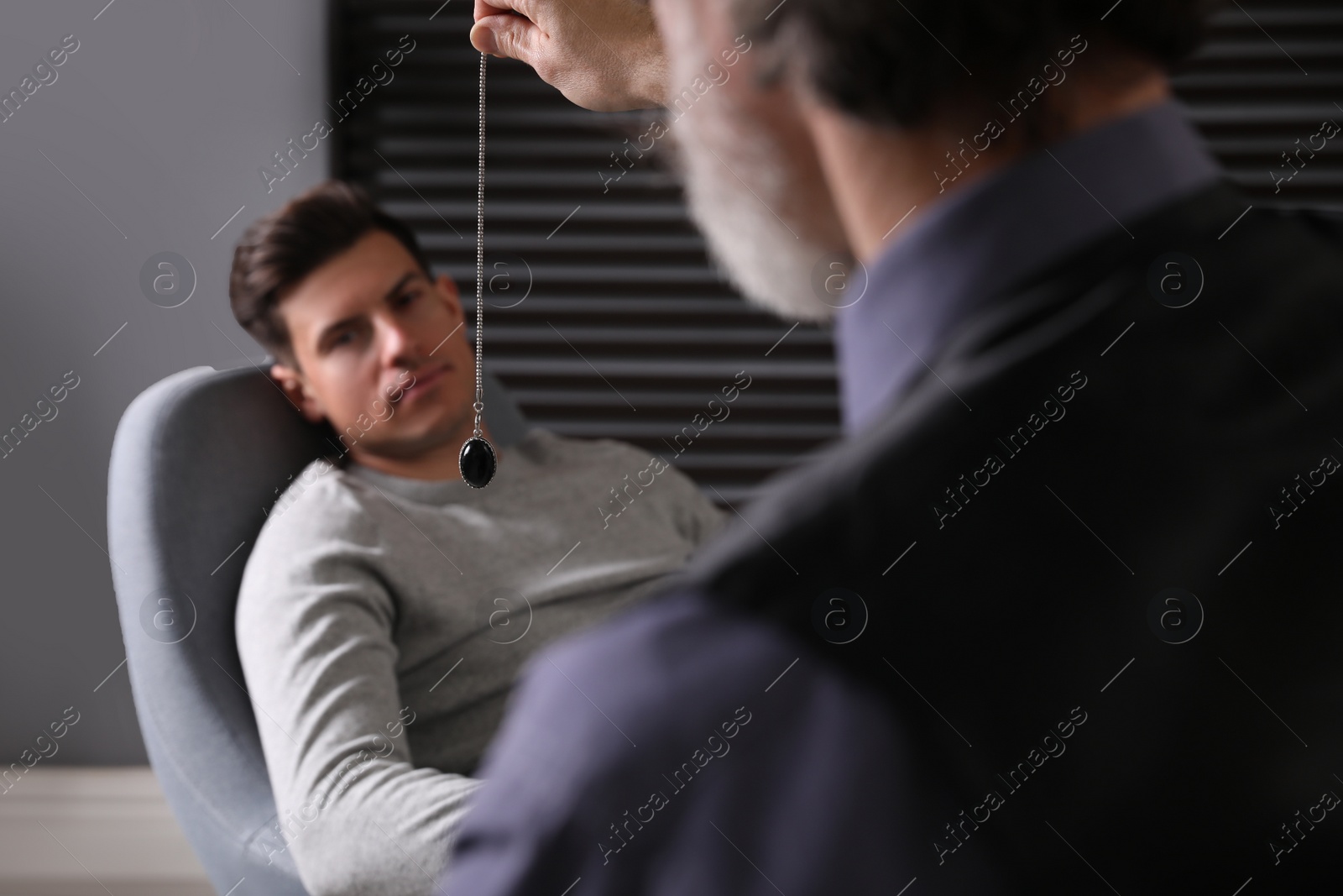 Photo of Psychotherapist using pendulum during hypnotherapy   session in office