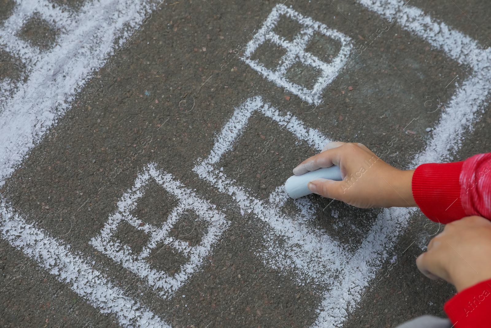 Photo of Child drawing house with chalk on asphalt, closeup