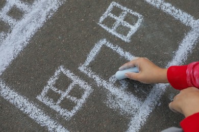 Child drawing house with chalk on asphalt, closeup