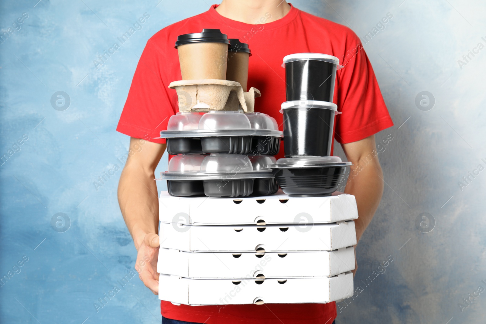 Photo of Courier with stack of orders on color background. Food delivery service