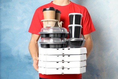 Photo of Courier with stack of orders on color background. Food delivery service