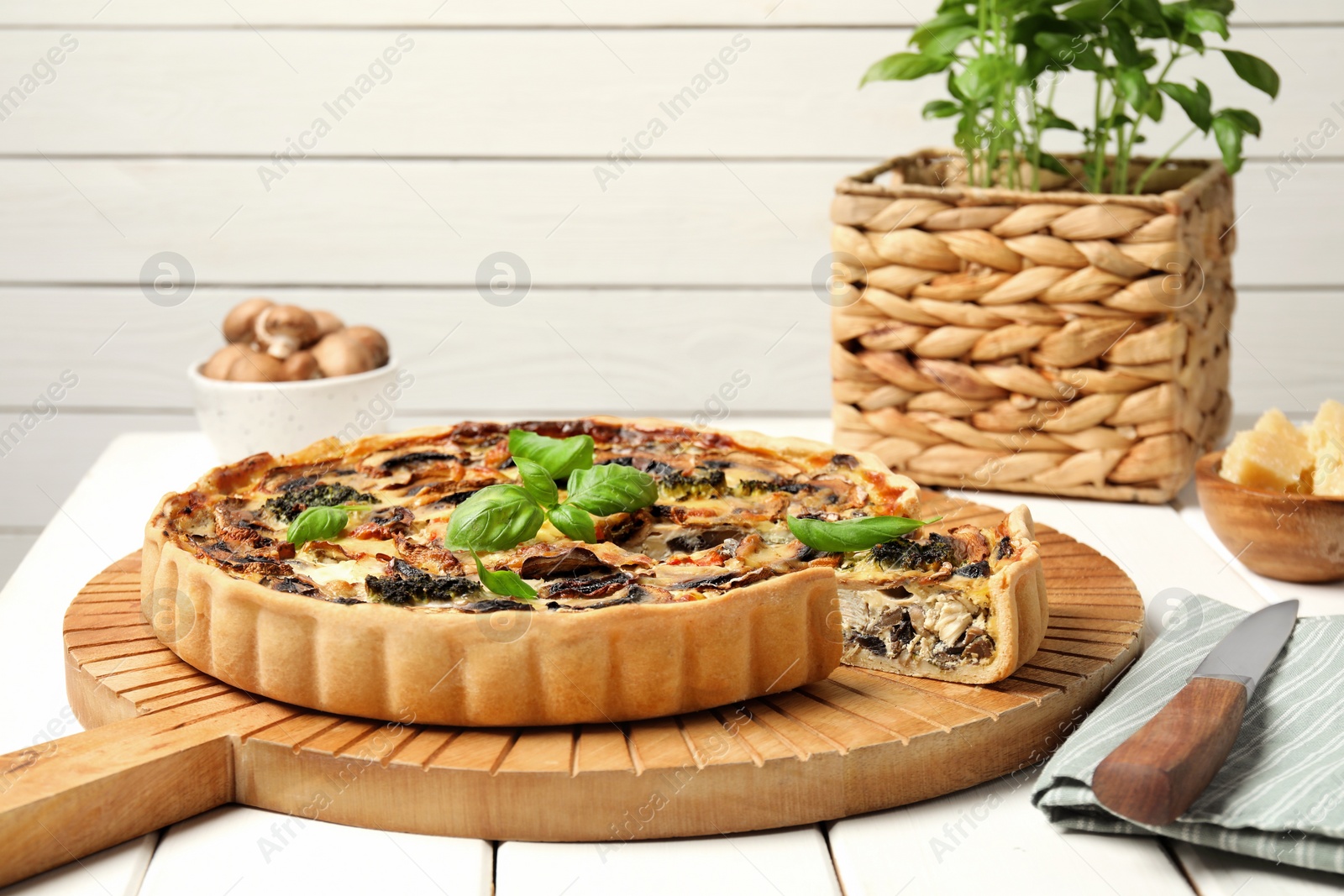 Photo of Delicious quiche with mushrooms and basil on white wooden table