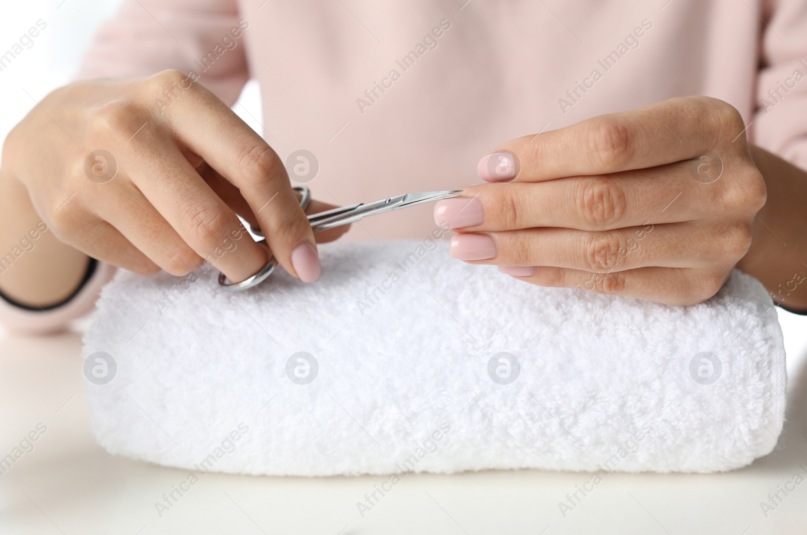 Photo of Woman cutting nails at table, closeup. At-home manicure
