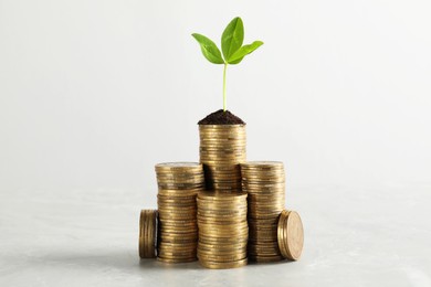 Photo of Stacked coins and green sprout on white marble table. Investment concept